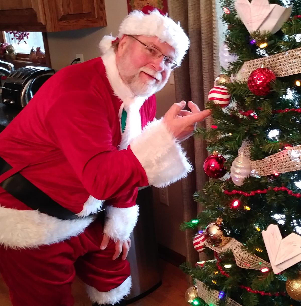 Santa bending next to tree.