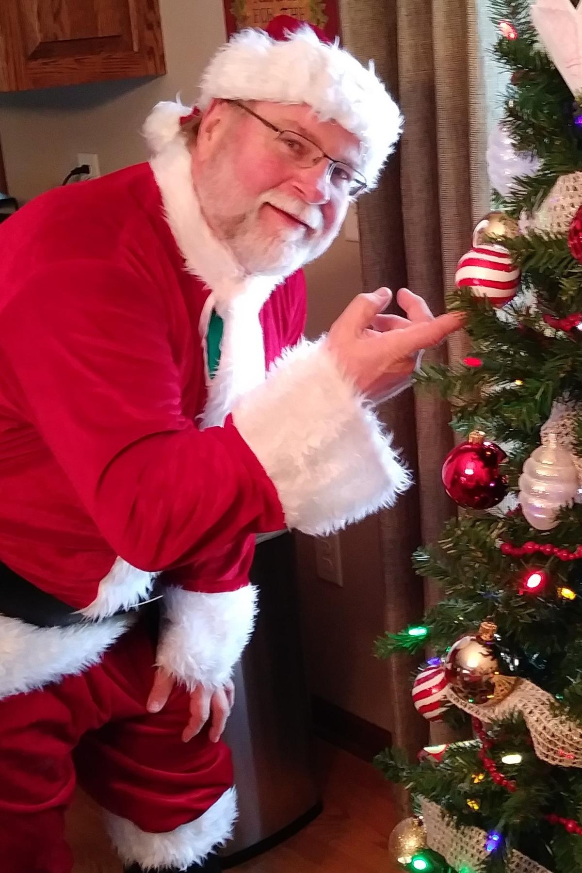 Santa bending next to a Christmas tree